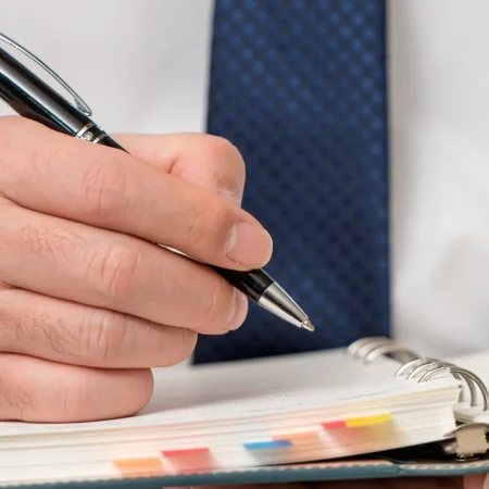 Senior business professional writing ideas on diary, Businessman making notes and planning strategy at desk, He is working in corporate office. Senior business professional writing ideas on diary, Businessman making notes and planning strategy at desk, He is working in corporate office.