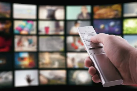 TV remote in hand on the background of the TV partenariat Bertelsmann RTL Group et OneStream