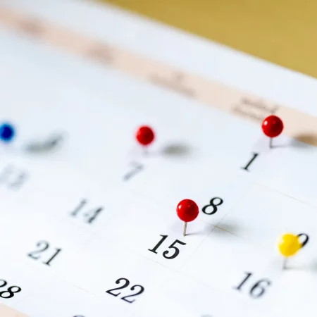 Closeup Colorful drawing pins on Calendar page with date Closeup Colorful drawing pins on Calendar page with date